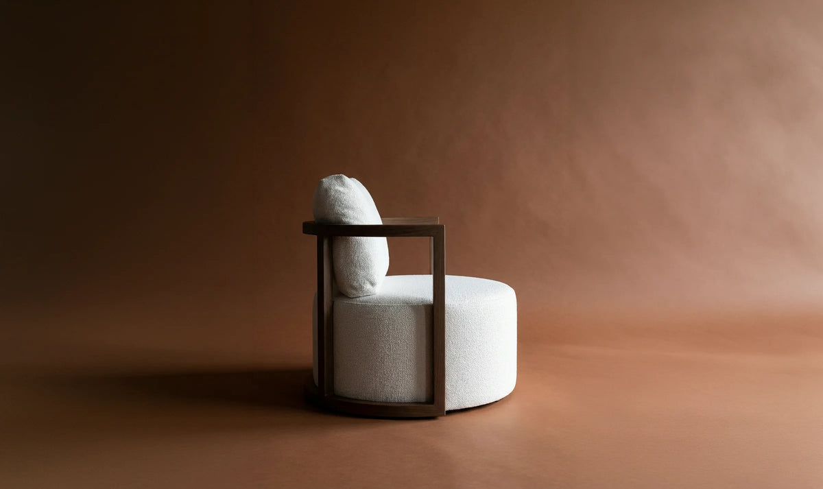 A Lanott boucle armchair with a walnut frame on a warm terracotta backdrop